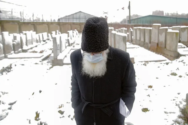 Rabbi Rafael Schaffer wears a face mask to protect against coronavirus, during the funeral of Iancu Tucarman, at a Jewish cemetery in Bucharest, Romania, Monday, January 11, 2021. Tucarman, one of the last remaining Holocaust survivors in Romania, on was buried after dying from COVID-19 last week at the age of 98. (Photo by Vadim Ghirda/AP Photo)