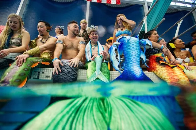 People dressed as mermaids and mermen sit on the side of the pool as they await the group photo and group swim during the MerMagic Convention at the Freedom Aquatic & Fitness Center in Manassas, Virginia on March 4, 2023. The event bills itself as the “World's Largest Mermaid Convention”. (Photo by Joseph Prezioso/AFP Photo)