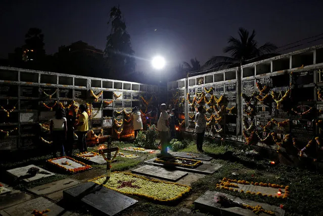 People pray beside the graves of their relatives at a cemetery during the observance of All Souls Day in Mumbai, India November 2, 2016. (Photo by Danish Siddiqui/Reuters)