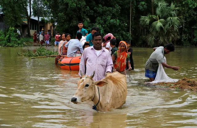 People wade through a flooded area after heavy rains at Mogpara village, south of Agartala, India, June 13, 2018. (Photo by Jayanta Dey/Reuters)