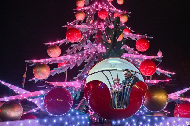 A father and his daughter ride a carousel during the Christmas Fair at Ukrainian National Exhibition Center in Kyiv on December 21, 2025, amid Russian invasion in Ukraine. (Photo by Sergei Supinsky/AFP via Getty Images)