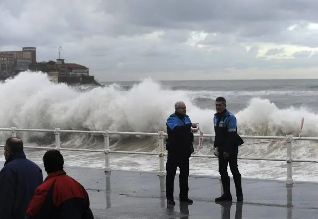 Policemen set up a cordoned area as people look on at the seawall on the San Lorenzo beach in Gijon, northern Spain, January 22, 2015. (Photo by Eloy Alonso/Reuters)