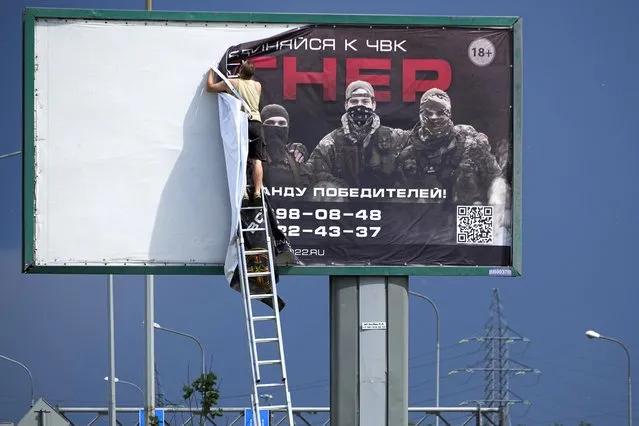 A man takes down the poster with writing reading “Join us at Wagner”, which is associated with the owner of the Wagner private military contractor, Yevgeny Prigozhin, is seen above a highway on the outskirts of St. Petersburg, Russia, Saturday, June 24, 2023. Russia's security services have responded to mercenary chief Prigozhin's declaration of an armed rebellion by calling for his arrest. In a sign of how seriously the Kremlin took the threat, security was heightened in Moscow, Rostov-on-Don and other regions. (Photo by AP Photo/Stringer)