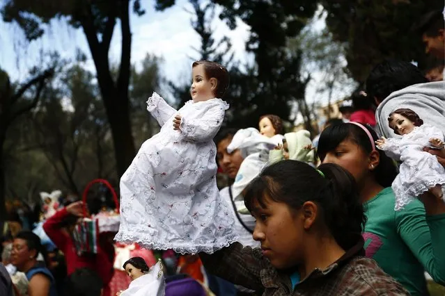 People lift up dressed-up dolls representing baby Jesus during a celebration 40 days after the birth of Jesus in Xochimilco, on the outskirts of Mexico City, February 2, 2015. (Photo by Edgard Garrido/Reuters)