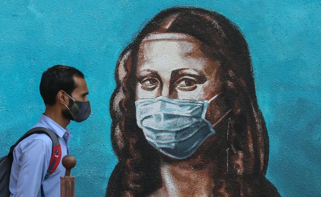 An Indian man walks past a wall showing a graffiti of Italian artist Leonardo da Vinci's Mona Lisa wearing a face mask, in Mumbai, India, 17 March 2021. India has recorded its highest two-day spike this year with over 20,000 Covid-19 cases reported from all over India. (Photo by Divyakant Solanki/EPA/EFE)