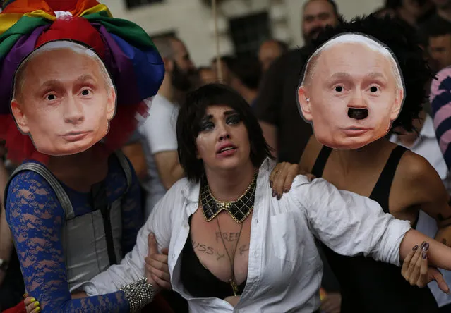 Activists stage a theatrical play where gay people are restrained by others wearing masks depicting Russian President Vladimir Putin, during a protest against Russia's new law on gays, in central London, Saturday, August 10, 2013. Hundreds of protesters, called for the Winter 2014 Olympic Games to be taken away from Sochi, Russia, because of a new Russian law that bans “propaganda of nontraditional sexual relations” and imposes fines on those holding gay pride rallies. (Photo by Lefteris Pitarakis/AP Photo)