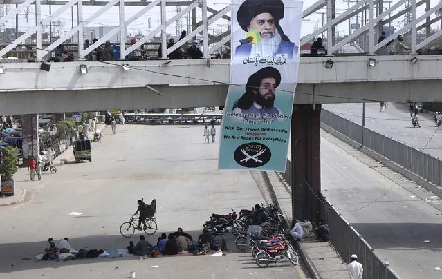 A banner with the portraits of Khadim Hussein Rizvi, top, and Saad Rizvi, leaders of Tehreek-e-Labiak Pakistan, a radical Islamist political party, hang on a bridge while their supporters block a road during a sit-in protest against the arrest of Rizvi, the head of their party, in Lahore, Pakistan, Wednesday, April 14, 2021. Pakistani security forces swinging batons and firing teargas moved before dawn Wednesday to clear sit-ins by protesting Islamists in the garrison city of Rawalpindi and elsewhere after five people died in earlier clashes, officials said. (Photo by K.M. Chaudary/AP Photo)