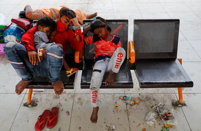 A migrant worker and his children sleep at a bus station as they wait to return to their village, after Delhi government ordered a six-day lockdown to limit the spread of the coronavirus disease (COVID-19), in Ghaziabad on the outskirts of New Delhi, India, April 20, 2021. (Photo by Adnan Abidi/Reuters)