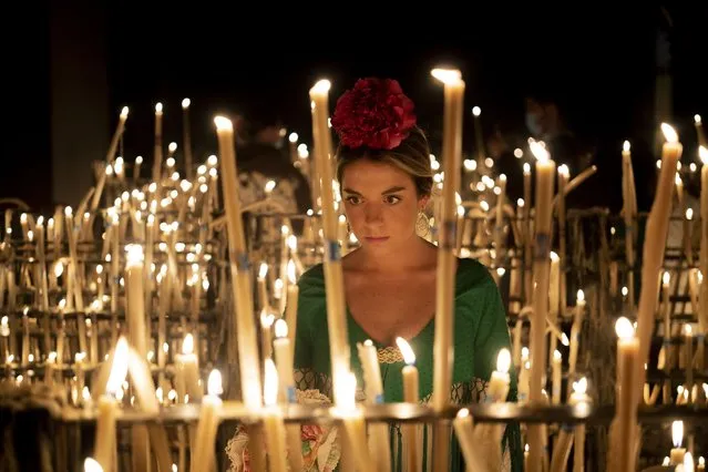 A pilgrim lights a candle in the sanctuary of the virgin of the Rocío in the village of El Rocío in Almonte, Spain, on Saturday June 4, 2022, during the annual pilgrimage in which hundreds of thousands of devotees of the Virgin del Rocio converge in and around the shrine. After a two-year hiatus forced by the pandemic, tens of thousands of pilgrims – many of them outfitted in tiered flamenco dresses, crisp riding suits and wide-brimmed Cordoba hats – descended on the tiny Spanish village of El Rocío to take part in riotously colorful and ancient festival, la Romería del Rocío, or the Rocío virgin pilgrimage. (Photo by Joan Mateu Parra/AP Photo)
