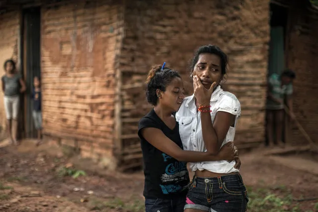 In this November 12, 2016 photo, Mariela Cabello, right, grieves after her brother was killed along with eight other villagers in Cariaco, Sucre state, Venezuela. Five law enforcement officers were charged with storming the village and killing nine men from a fishing family, who were widely thought to have belonged to a gang. (Photo by Rodrigo Abd/AP Photo)