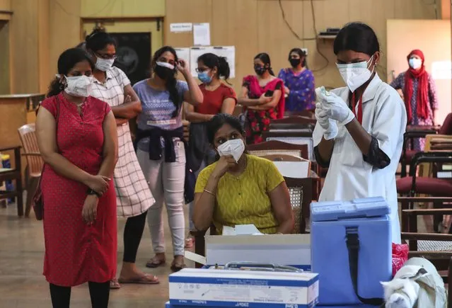 An Indian nurse prepares to administer a dose of Covishield, Serum Institute of India’s version of the AstraZeneca vaccine to a woman as others wait their turn in Bengaluru, India, Wednesday, May 19, 2021. India has the second-highest coronavirus caseload after the U.S. with more than 25 million confirmed infections. (Photo by Aijaz Rahi/AP Photo)