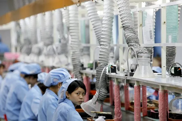 An employee looks up while working along a production line in Suzhou Etron Electronics Co. Ltd's factory in Suzhou, Jiangsu province in this June 8, 2010 file photo. (Photo by Aly Song/Reuters)