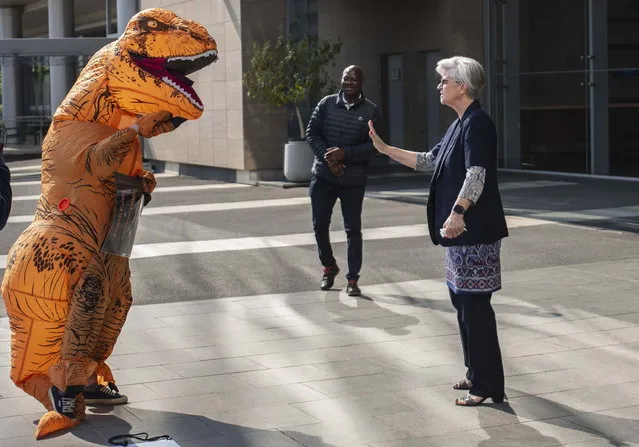 A member of Standard Bank security personnel ordering an Extinction Rebellion activist wearing a dinosaur to leave the area during an occupation protest outside the offices of Standard Bank South Africa in Johannesburg, South Africa, 19 September 2023. Extinction Rebellion is protesting against Standard Bank's investment in  fossil fuel related projects in the country. South Africa electricity generation is largely supported by coal fired power stations. (Photo by Kim Ludbrook/EPA)