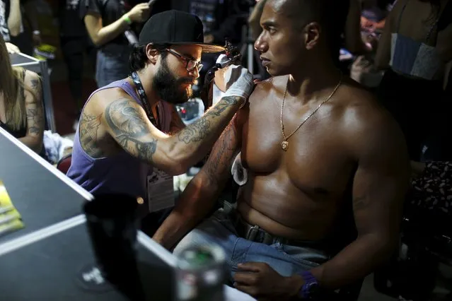 An artist works on a tattoo on a man's shoulder during the third International Tattoo Week Rio 2016 festival in Rio de Janeiro, Brazil, January 22, 2016. (Photo by Pilar Olivares/Reuters)