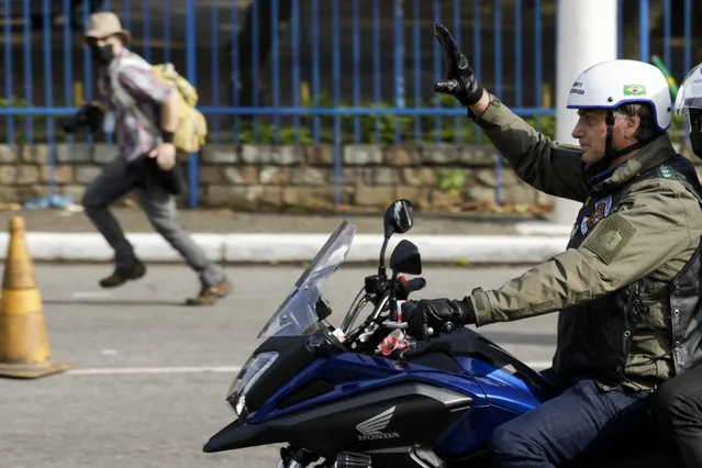 Brazil's President Jair Bolsonaro, waves as he leads a caravan of motorcycle enthusiasts following him through the streets of the city, in a show of support for Bolsonaro, in Sao Paulo, Brazil, Saturday, June 12, 2021. (Photo by Marcelo Chello/AP Photo)