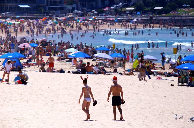 People wearing Christmas hats walk across the sand as they celebrate Christmas Day at Sydney's Bondi Beach in Australia, December 25, 2016. (Photo by David Gray/Reuters)