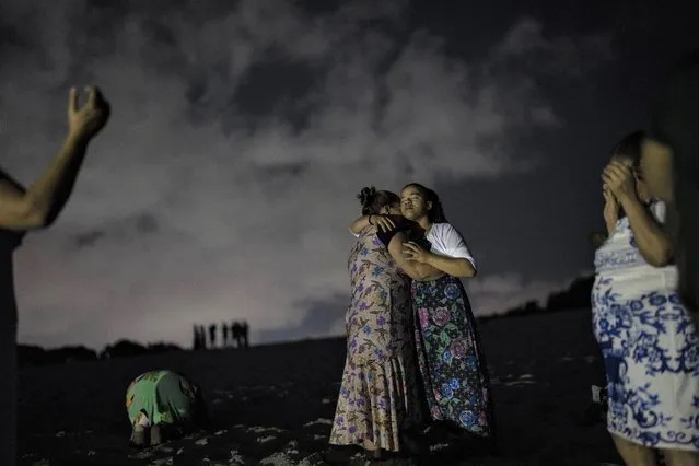 Mag Oliveira embraces her daughter Najla as they pray in an area of the Abaete dune system, on a steep rise of sand evangelicals have come to call the “Holy Mountain”, in Salvador, Brazil, late Friday night, September 16, 2022. Evangelicals have been converging on the dunes for some 25 years but especially lately, with thousands now coming each week to sing, pray and enter trancelike states to commune with God. (Photo by Rodrigo Abd/AP Photo)