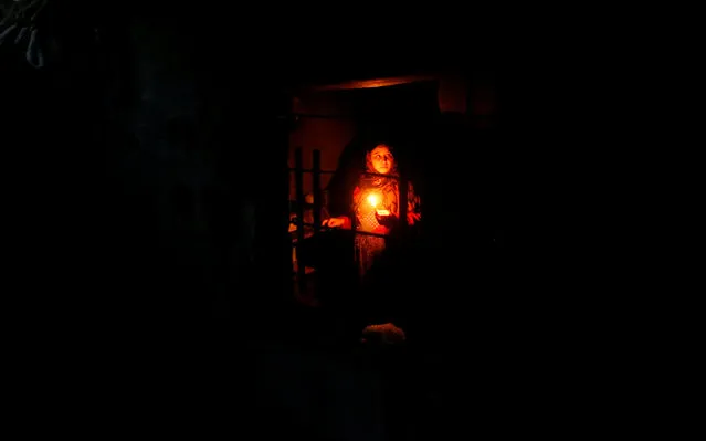 A Palestinian woman uses a candle light as she works in her kitchen during a power cut inside her house in Beit Lahiya in the northern Gaza Strip January 11, 2017. (Photo by Mohammed Salem/Reuters)