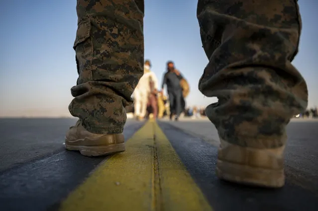 In this image provided by the U.S. Air Force, a U.S. Marine provides security for evacuees boarding a U.S. Air Force C-17 Globemaster III at Hamid Karzai International Airport in Kabul, Afghanistan, Tuesday, August 24, 2021. (Photo by Senior Airman Taylor Crul/U.S. Air Force via AP Photo)