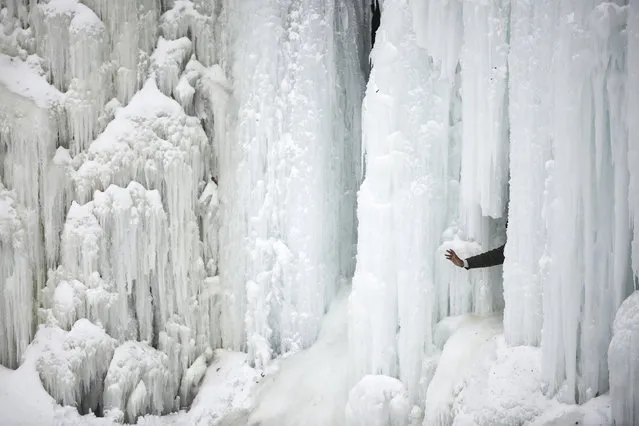 A person waves for a photo from behind frozen Minnehaha Falls Saturday, February 2, 2019, in Minneapolis. (Photo by Aaron Lavinsky/Star Tribune via AP Photo)