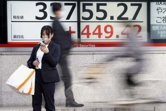 A person stands in front of an electronic stock board showing Japan's Nikkei 225 index at a securities firm on December 27, 2023, in Tokyo. Asian shares were mixed in muted trading on Friday, Dec. 29, the last trading day of the year, with some regional markets logging solid gains in 2023 while many sagged. (Photo by Eugene Hoshiko/AP Photo)