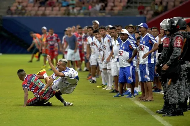 Alvorada striker Neymar Junior, center, falls while fighting for the ball as players invade the pitch during the Peladao final amateur soccer tournament at Arena da Amazonia in Manaus, Brazil, Saturday, February 16, 2019. Many players had eye-catching hairstyles, many trying to copy whatever style Neymar had throughout his career and others whose hair carries inscriptions like “I love Jesus”. (Photo by Victor R. Caivano/AP Photo)