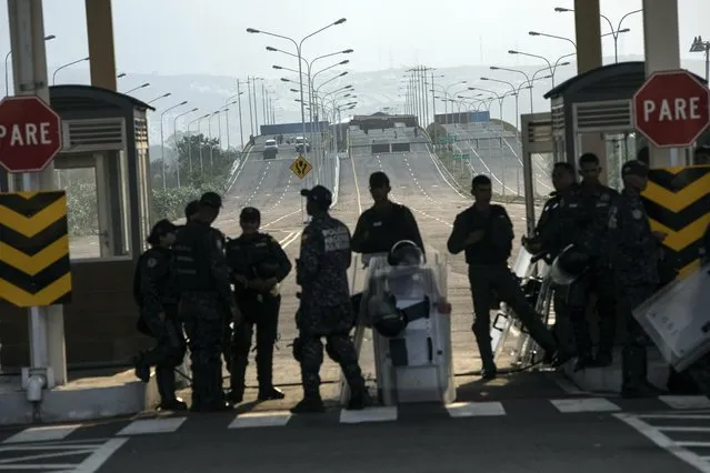 Policemen stand guard during a concert at Tienditas International Bridge, in Venezuela, Friday, February 22, 2019, on the border with Colomcia. Venezuela's power struggle is set to convert into a battle of the bands Friday when musicians demanding Nicolas Maduro allow in humanitarian aid and those supporting the embattled leader's refusal sing in rival concerts being held at both sides of a border bridge where tons of donated food and medicine are being stored. (Photo by Rodrigo Abd/AP Photo)