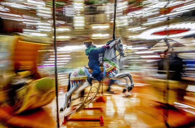 A child rides on a horse on a merry-go-round at the Christmas market in Frankfurt, Germany, Wednesday, November 29, 2023. (Photo by Michael Probst/AP Photo)