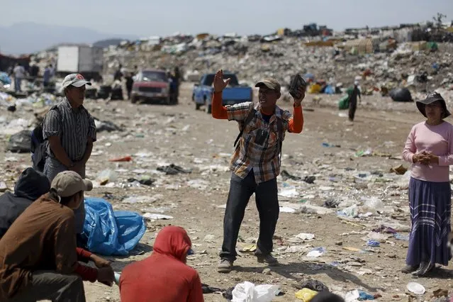 A man who lives on selling usable items found in a dumpsite, preaches to fellow workers on the outskirts of Tegucigalpa April 17, 2015. At the dumpsite people scavenge through the garbage looking for usable items like plastic, metals and cardboard to sell and recycle, making some 100 Lempiras ($4.80) per day, according to local media. (Photo by Jorge Cabrera/Reuters)