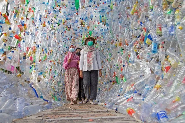 People walk through “Terowongan 4444” or 4444 tunnel, built from plastic bottles collected from several rivers around the city in three years, at the plastic museum constructed by Indonesia's environmental activist group Ecological Observation and Wetlands Conservation (ECOTON) in Gresik regency near Surabaya, East Java province, Indonesia, September 28, 2021. (Photo by Prasto Wardoyo/Reuters)