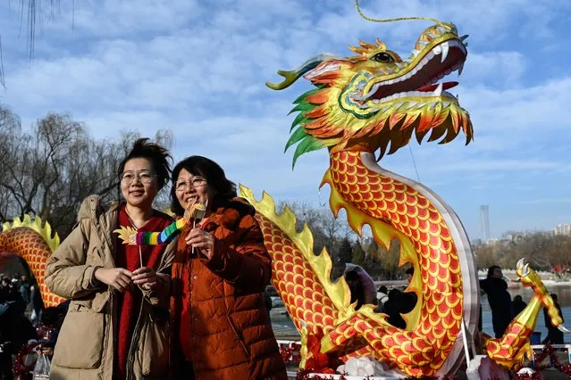 Women pose for a picture next to a dragon figure at the Longtan park fair on the second day of the Lunar New Year of the Dragon in Beijing on February 11, 2024. (Photo by Pedro Pardo/AFP Photo)
