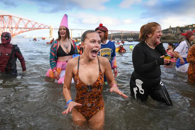 Members of the public join New Year swimmers, many in costume, in front of the Forth Rail Bridge during the annual Loony Dook Swim in the River Forth on January 1, 2019 in South Queensferry, near Edinburgh, Scotland. Tens of thousands of people gathered last night in Edinburgh and other events across Scotland to see in the New Year at Hogmanay celebrations. (Photo by Jeff J. Mitchell/Getty Images)