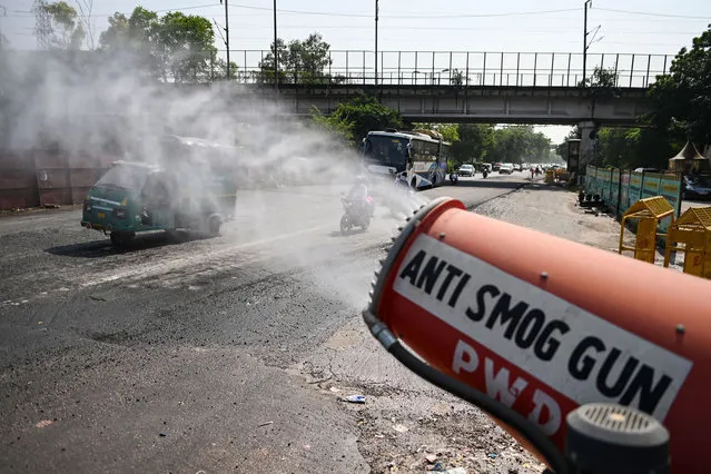 An anti-smog gun operates to curb air pollution as vehicles make their way along a road in New Delhi on October 25, 2021. (Photo by Sajjad Hussain/AFP Photo)