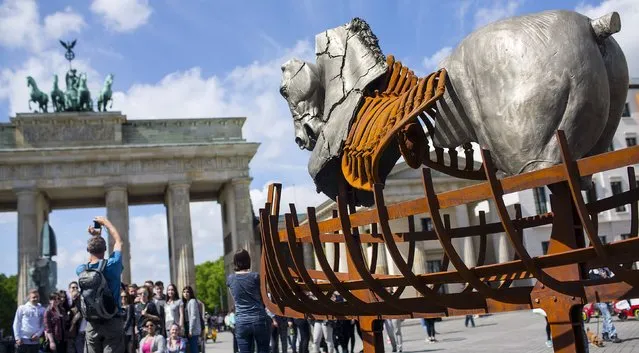 A man takes a picture near a piece of a travelling art exhibition called “Lapidarium” by Mexican artist Gustavo Aceves, in front of Brandenburg Gate in Berlin, Germany, May 4, 2015. The artwork is made up of 20 giant horses made of Italian marble, bronze, cast iron and granite, with some of them reaching six metres (19.7 ft) in height. (Photo by Hannibal Hanschke/Reuters)