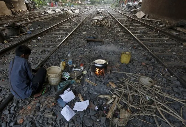 Ratan Samanta, 29, cooks a meal between the railway tracks in a slum area of Kolkata, India, March 13, 2016. (Photo by Rupak De Chowdhuri/Reuters)