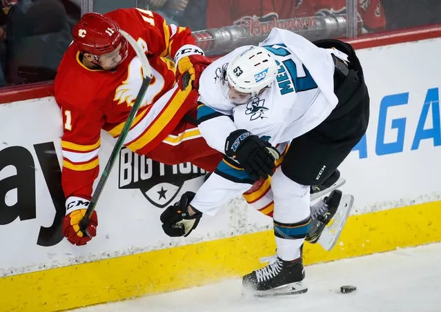 San Jose Sharks' Nicolas Meloche, right, checks Calgary Flames' Mikael Backlund during the first period of an NHL hockey game, Tuesday, November 9, 2021 in Calgary, Alberta. (Photo by Jeff McIntosh/The Canadian Press via AP Photo)