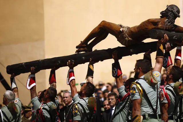 Spanish legionnaires sing an anthem as they carry a statue of the Christ of Mena outside a church during a ceremony before they take part in the “Mena” brotherhood procession in Malaga, southern Spain, March 24, 2016. (Photo by Jon Nazca/Reuters)