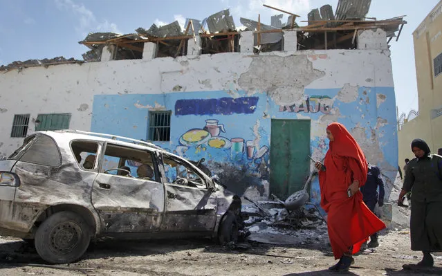 A female police officer inspects the scene of a car bomb attack outside a restaurant in the capital Mogadishu, Somalia Saturday, April 9, 2016. A Somali police official says two people have been killed in a car bombing at a restaurant where dozens of people were dining, in the capital Saturday. (Photo by Farah Abdi Warsameh/AP Photo)