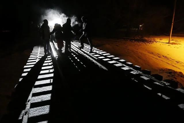 Migrants from Somalia cross into Canada from the United States by walking down a train track early Sunday, February 26, 2017, into the town of Emerson, Manitoba, where they will seek asylum at the Canada Border Services Agency. (Photo by John Woods/The Canadian Press via AP Photo)