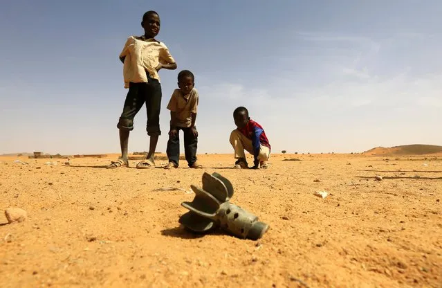 Children look at the fin of a mortar projectile that was found at the Al-Abassi camp for internally displaced persons after an attack by rebels in Mellit town, North Darfur, March 25, 2014. (Photo by Mohamed Nureldin Abdallah/Reuters)