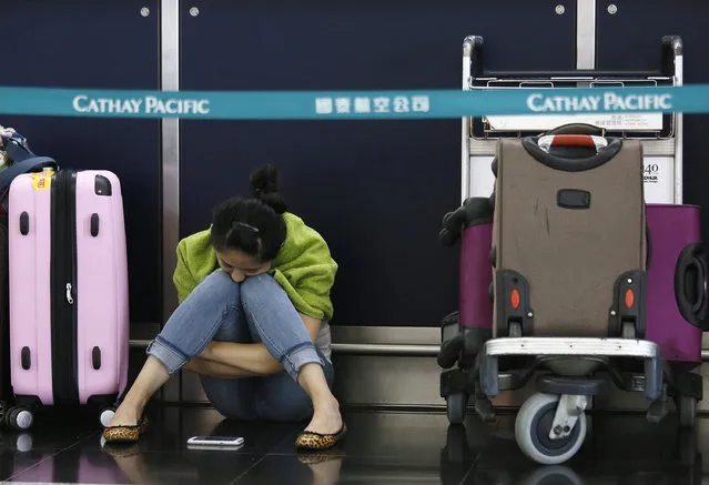 A passenger waits for flights to resume while sitting an airline counter at Hong Kong's international airport after Typhoon Usagi slammed into southern China, Monday, September 23, 2013. (Photo by Vincent Yu/AP Photo)