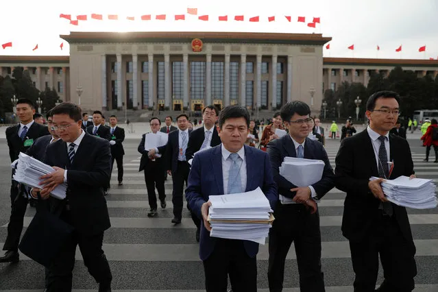 People carry stacks of papers near the Great Hall of the People after a plenary session of the Chinese People's Political Consultative Conference (CPPCC) in Beijing, China, March 11, 2017. (Photo by Damir Sagolj/Reuters)