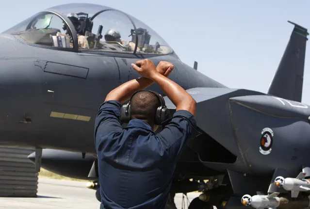 A member of the ground crew signals to the pilot of a U.S. Air Force F-15E fighter jet before take off at Bagram air base, north of Kabul, August 10, 2009. (Photo by Oleg Popov/Reuters)