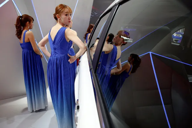 Performers are reflected in a displayed vehicle before going onto the stage during the Auto China 2016 auto show in Beijing, China, April 29, 2016. (Photo by Damir Sagolj/Reuters)