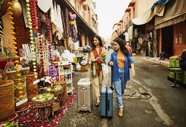 Wide shot of female friends walking with luggage through the souks of Marrakech while on vacation on March 27, 2024. (Photo by Thomas Barwick/Getty Images)