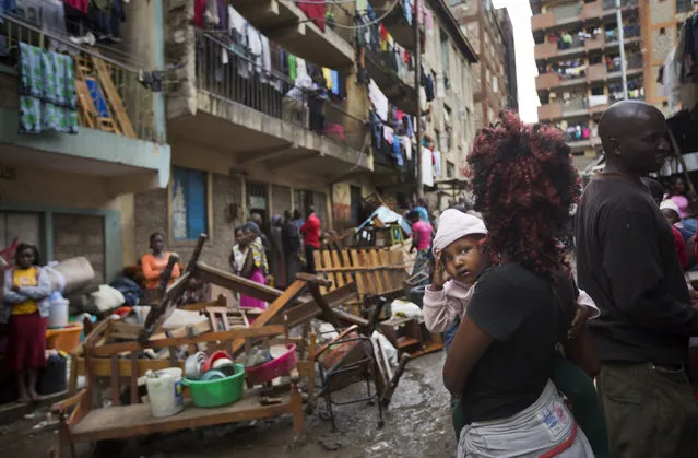 A woman holds a baby as residents are evicted from their apartment blocks close to the site of last week's building collapse, after their homes were deemed unfit for habitation and marked for demolition, in the Huruma neighborhood of Nairobi, Kenya, Friday, May 6, 2016. As emergency workers retrieved more bodies from a building that collapsed a week ago, bringing the death toll to 41, hundreds of residents were evicted from nearby buildings that are being torn down to prevent other disasters. (Photo by Ben Curtis/AP Photo)