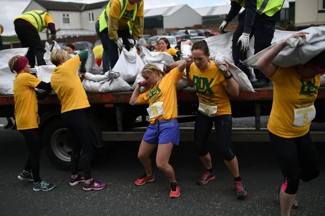 Competitors take part in the Women' s Race at the annual World Coal Carrying Championships in the village of Gawthorpe, near Wakefield, northern England on April 17, 2017. The World Coal Carrying Championships, which began in 1963, takes place on Easter Monday and challenges participants to race with a sack of coal for just over one kilometre to secure the best time. The event features Men' s, Women' s and Children' s races with Men carrying 50 kg of coal and women 20 kg in weight. To finish the sack of coal must be dropped on the Village Green where the traditional Maypole is situated in the heart of Gawthorpe. (Photo by Oli Scarff/AFP Photo)