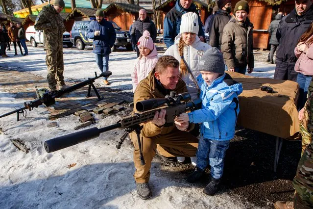 A participant of an open civil defence exercise shows a rifle to a boy, Uzhhorod, western Ukraine on February 13, 2022. (Photo by Serhii Hudak/Ukrinform/Future Publishing via Getty Images)