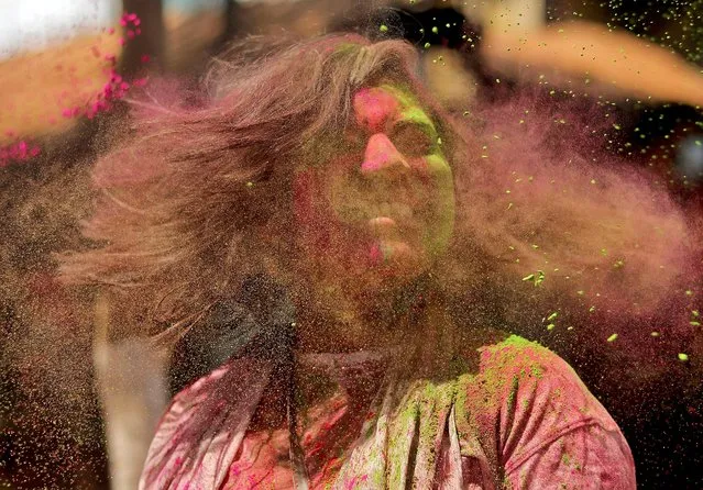 A woman daubed in colours shakes her head to remove the coloured powder during Holi celebrations in Mumbai, India, March 18, 2022. (Photo by Niharika Kulkarni/Reuters)