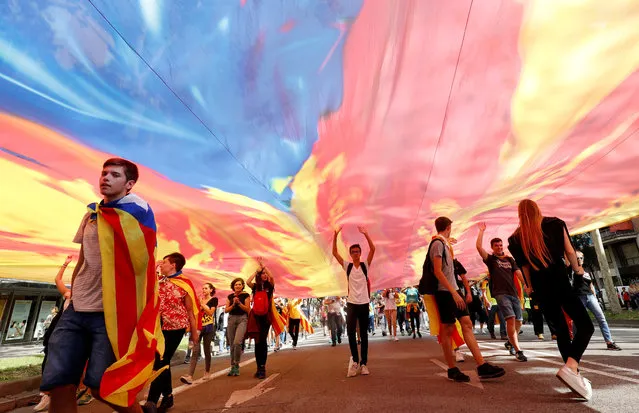 Demonstrators walk under an Estelada (Catalan separatist flag) as they march on Diagonal Avenue during Catalonia's general strike in Barcelona, Spain, October 18, 2019. (Photo by Albert Gea/Reuters)